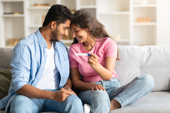 Indian couple smiling with positive pregnancy test Indian couple smiling with positive pregnancy test
